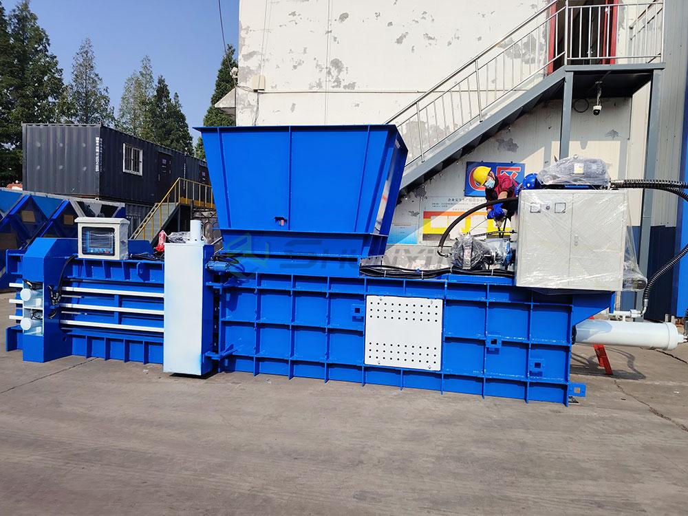 horizontal hydraulic baler compressing cardboard in factory